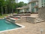 Patio at rear of house, in Geauga County Ohio, featuring spa and pool.  The architect used stone wall planters beside steps.